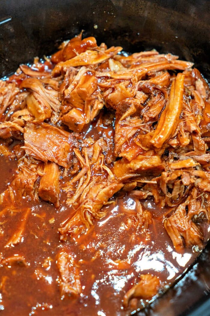 Savor the taste of pulled pork simmering in a rich barbecue sauce, effortlessly crafted with 2 ingredients in a slow cooker.