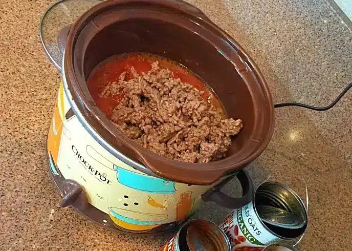A Crock-Pot filled with browned ground beef and tomato sauce.