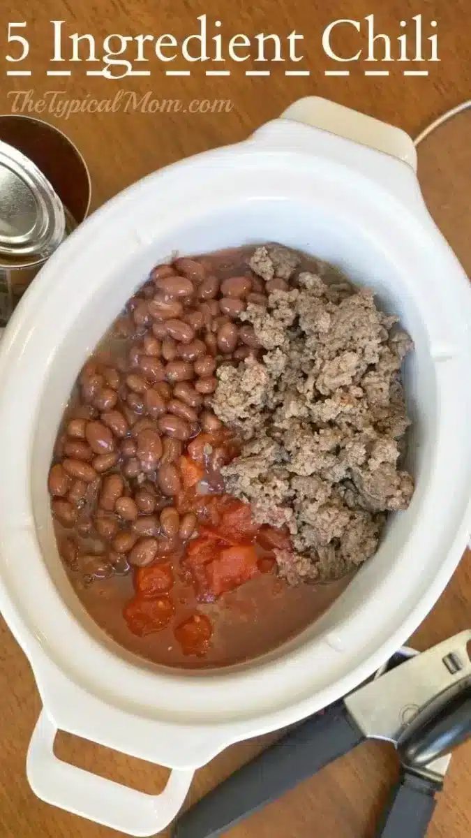 An overhead view of a white slow cooker containing 5-ingredient chili. The chili consists of beans, ground meat, and diced tomatoes.