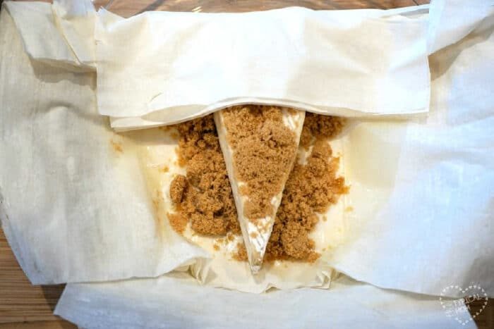 Brie cheese topped with brown sugar, wrapped in parchment paper, becomes irresistible when transformed