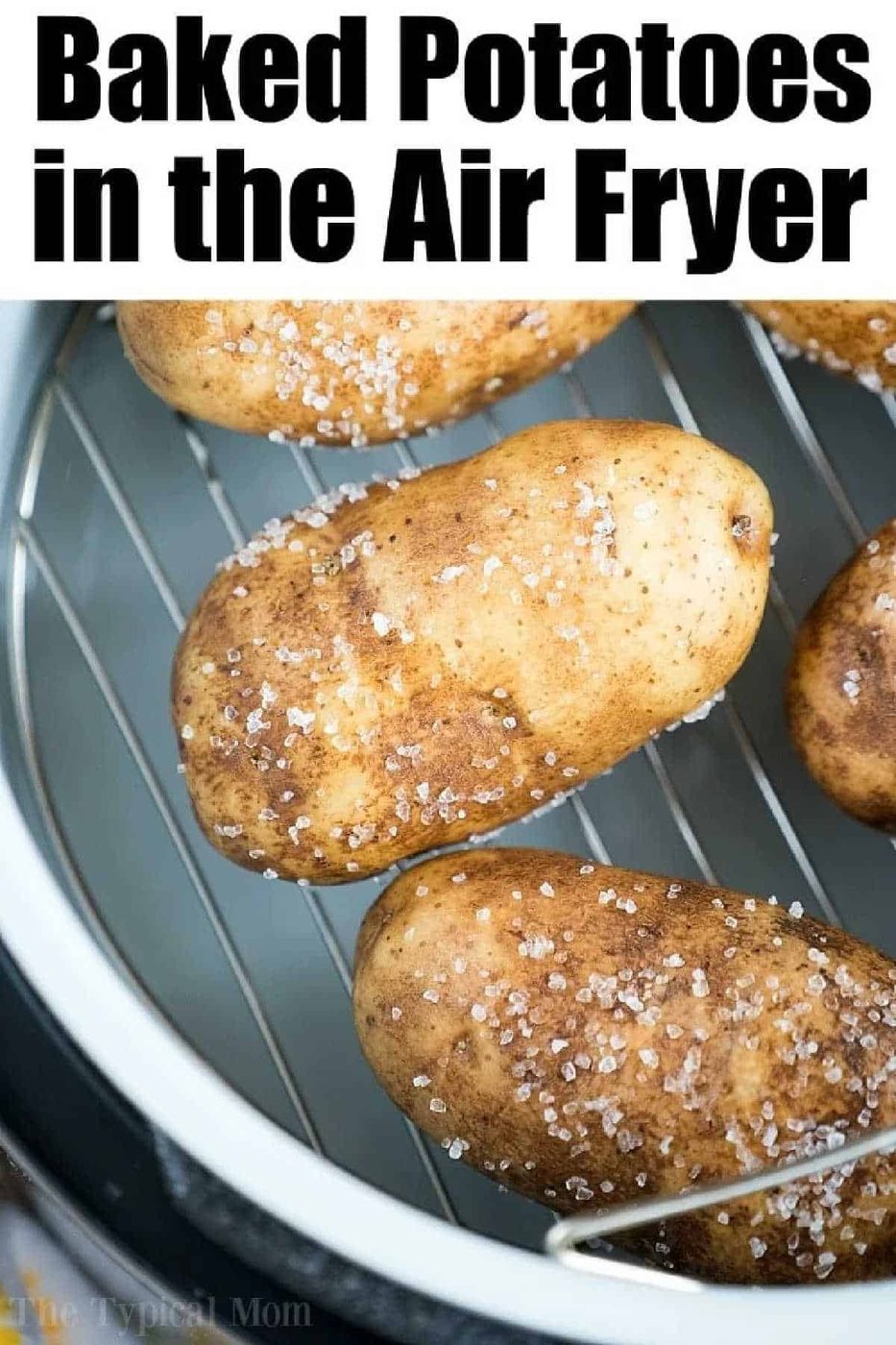 Four salted russet potatoes on a metal rack inside an air fryer, ready for baking the solid air fryer baked potatoes.