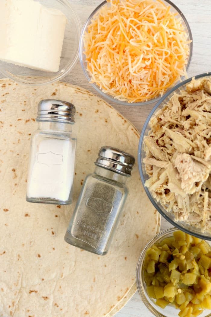 Ingredients for air fryer chimichangas: tortilla, shredded cheese, shredded chicken, jalapeños, butter, salt, and pepper.