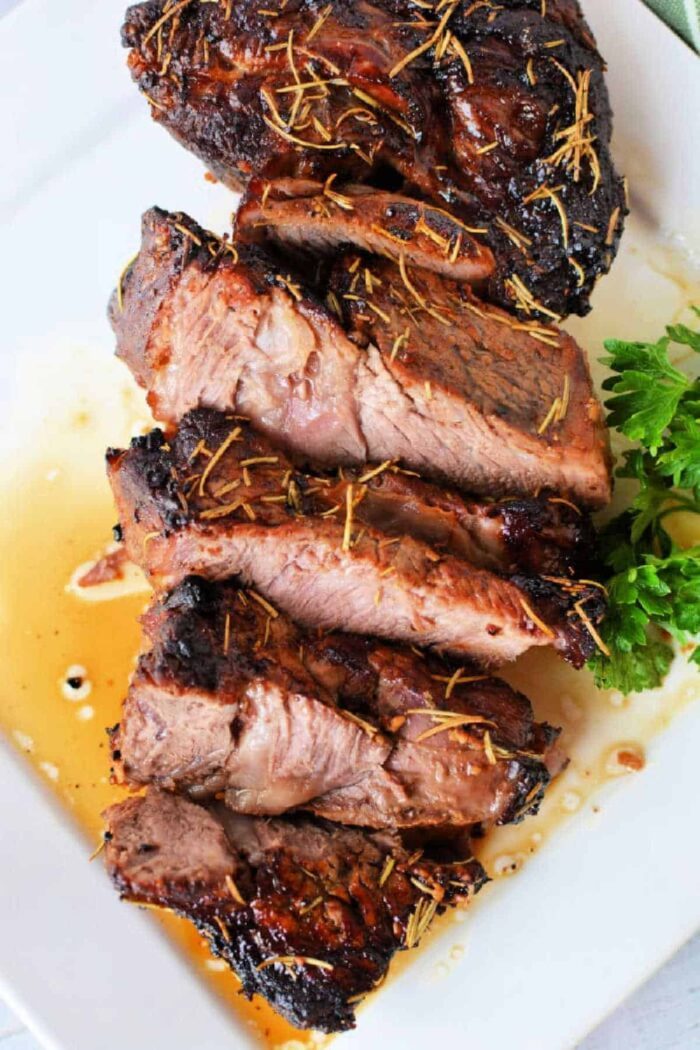 air fried chuck roast with rosemary on a white plate, expertly prepared using an air fryer chuck roast technique, and garnished with fresh parsley.