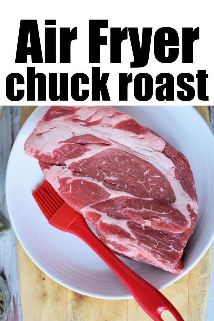 A raw beef chuck roast for an air fryer chuck roast recipe sits on a white plate next to a red silicone basting brush.