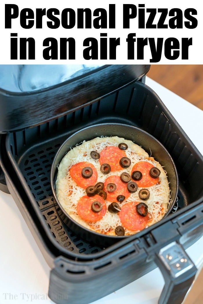 An air fryer is open, revealing a personal pizza with cheese, pepperoni, and black olives nestled inside. The text "Air Fryer Pizza" elegantly hovers above the image.