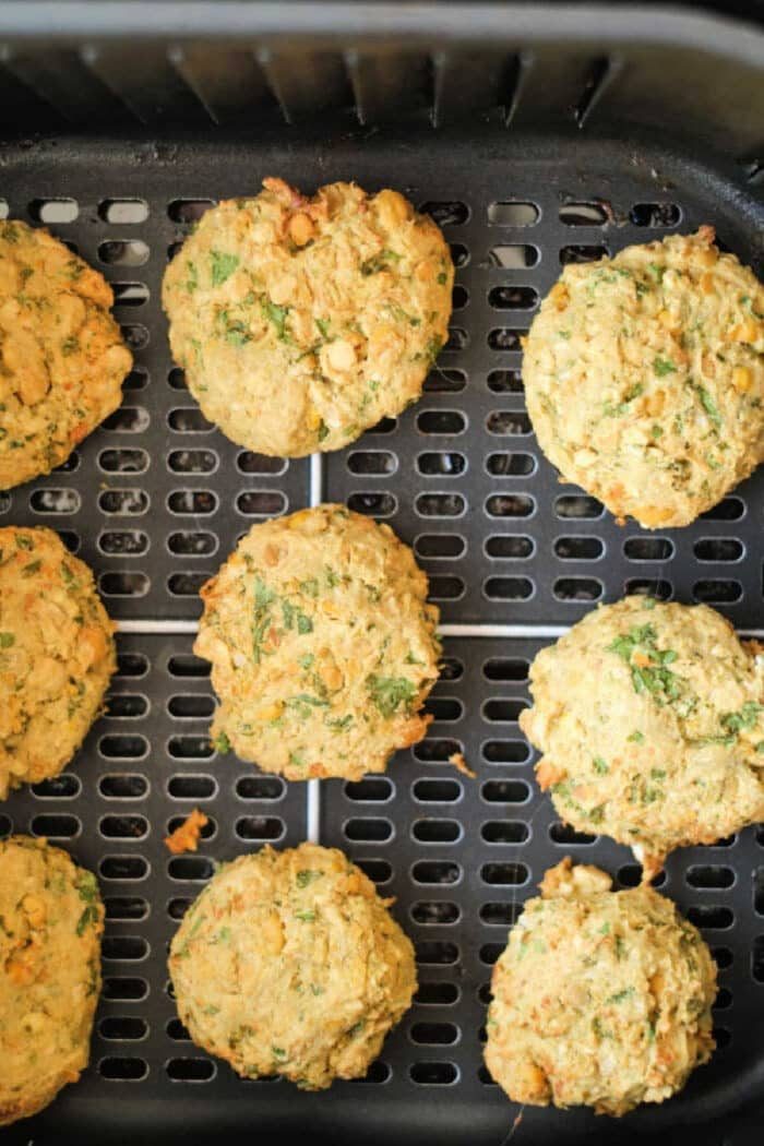 Nine air fryer falafel patties on a tray, golden brown and flecked with herbs.