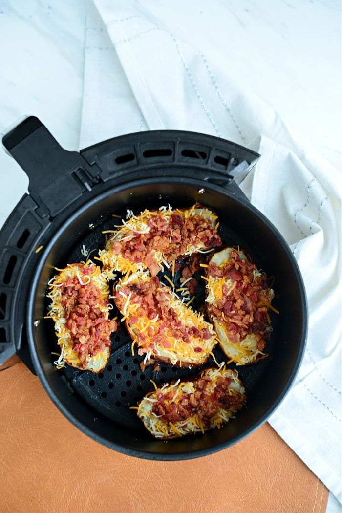 Air fryer potato skins loaded with melted cheese and crispy bacon bits make for the solid snack.
