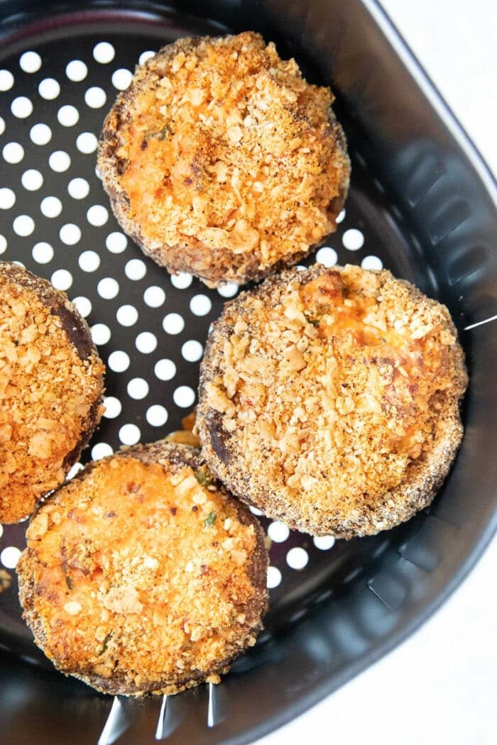 Four air fryer stuffed mushrooms with a golden breadcrumb topping served fresh from the basket.