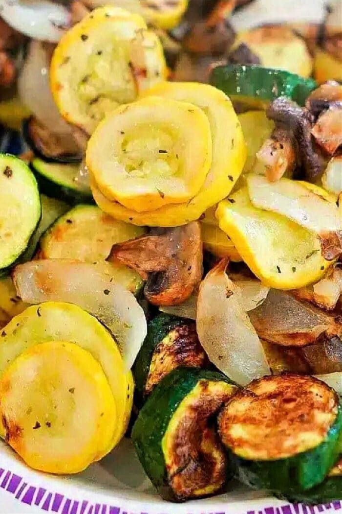 Sautéed yellow squash, zucchini, onions, and mushrooms—good air fryer vegetables—served on a white plate with a purple border.