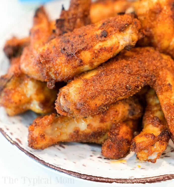 A plate filled with crispy, golden brown dry rub air fryer wings stacked on top of each other. The wings are seasoned with visible spices and appear to be freshly cooked. The edges of the plate are slightly visible, making this recipe a feast for both the eyes and taste buds.