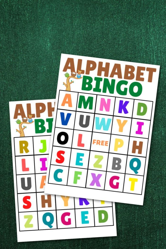 Two vibrant alphabet bingo cards rest on a green textured background, ready for your next game.