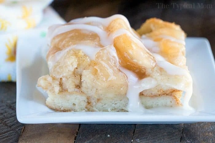 Close-up of a glazed apple pie bread pudding slice, reminiscent of bread pudding, on a white plate.