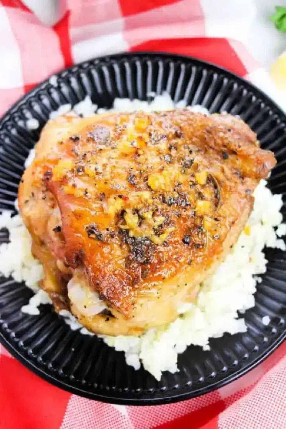 Roast chicken thigh with herbs served on a bed of white rice on a black plate—solid inspiration if you're wondering how long to bake bone-in chicken thighs at 350 for tender, flavorful results.