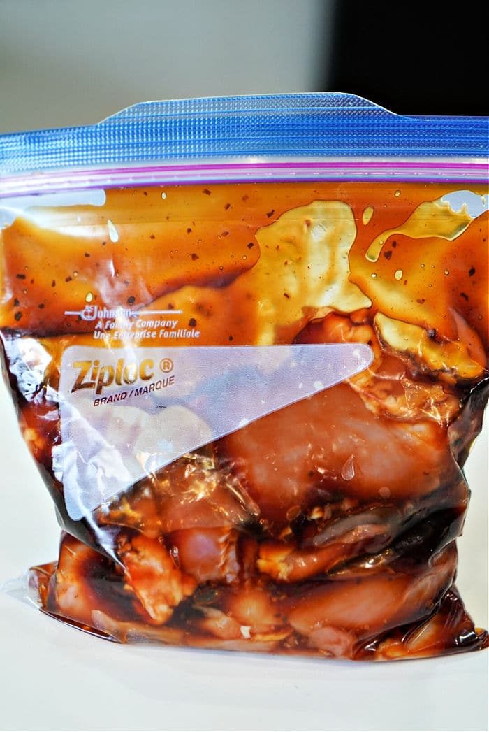A plastic zip-lock bag filled with marinating chicken in a dark sauce, soon to become good baked teriyaki chicken thighs.