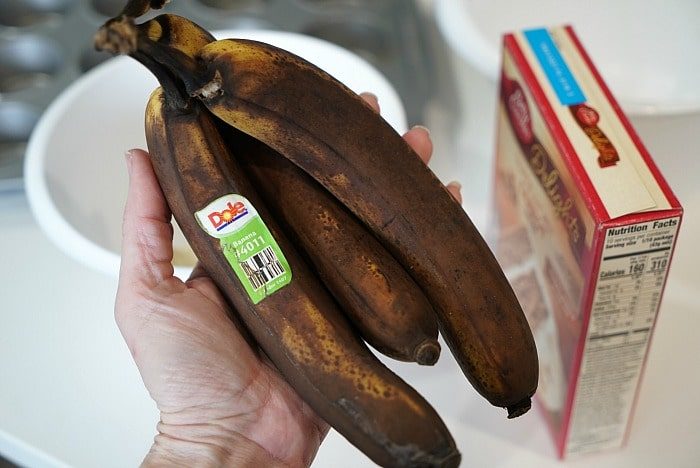 A person holds ripe bananas, poised to whip up a recipe, with a cake mix box conveniently nearby.