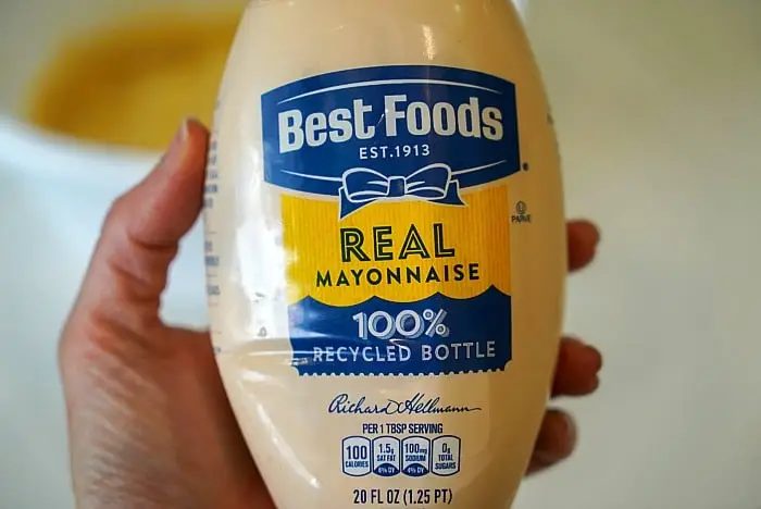 A person holds a 20 fl oz bottle of Best Foods Real Mayonnaise, labeled "100% Recycled Bottle." solid for crafting the ultimate bang bang shrimp sauce, this mayo offers 100 calories per tablespoon serving and nutrition facts right on the label.