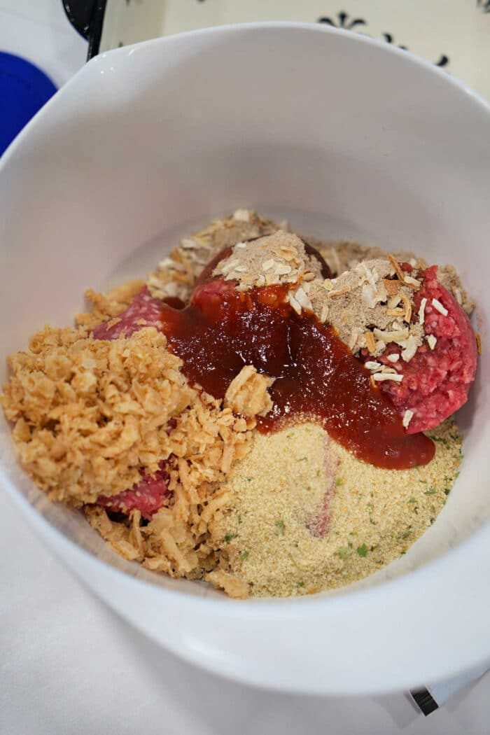 Unmixed meatloaf ingredients in a bowl, including ground beef, breadcrumbs, crushed chips, and sauce—solid for starting your favorite BBQ meatloaf recipe.