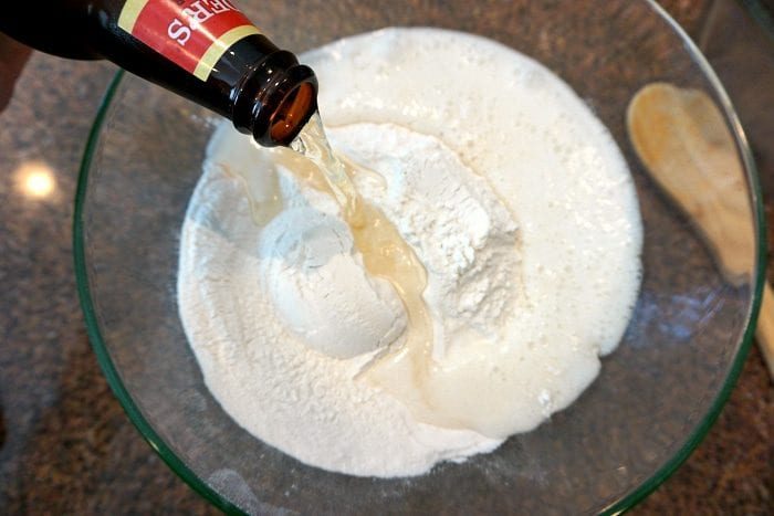 Pouring the best beer for bread into flour in a glass bowl creates a delightful fusion of flavors.
