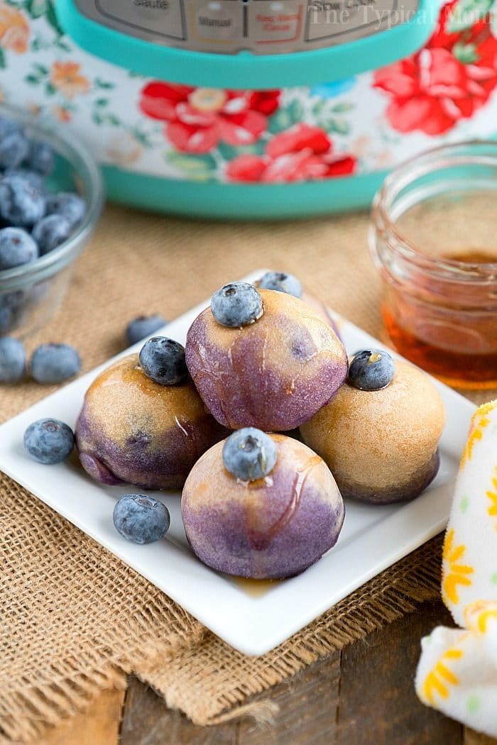Blueberry pancake bites on a square white plate, garnished with fresh blueberries and drizzled with syrup, resemble delightful Instant Pot pancake bites that elevate any breakfast spread.