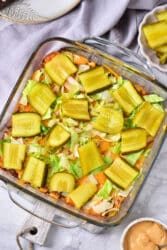 Big Mac Casserole topped with sliced pickles and lettuce in a glass baking dish.