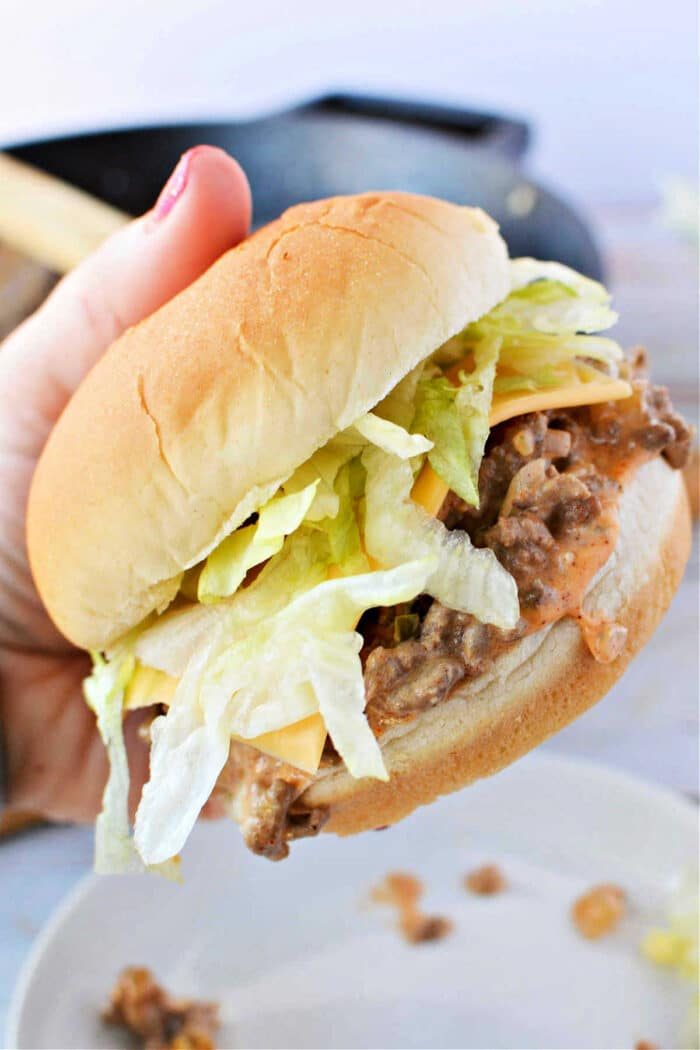 A hand holds a Big Mac, brimming with lettuce and juicy ground beef.