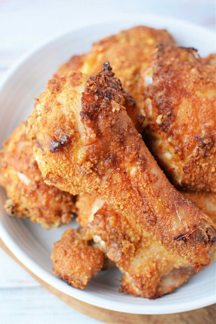 A plate of golden-brown Bisquick oven-fried chicken drumsticks and thighs.
