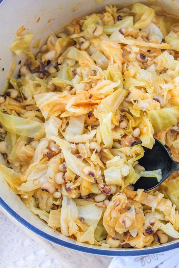 A savory pot of Black Eyed Peas and Cabbage awaits, complete with a spoon.