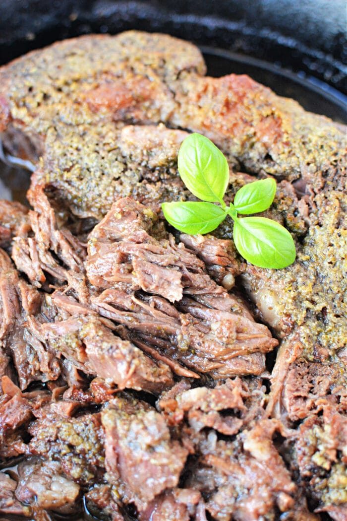 A close-up of perfectly cooked boneless beef topped with fresh green basil leaves.