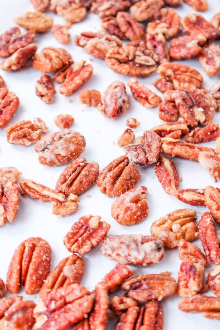 A close-up of assorted candied pecans prepared on the stove, scattered on a white surface.