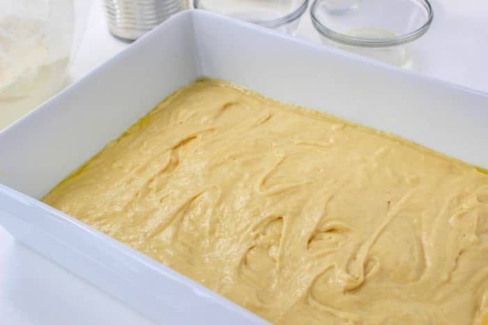 Yellow cake batter spread evenly in a white rectangular baking dish, ready to be baked into a good Cherry Coffee Cake.