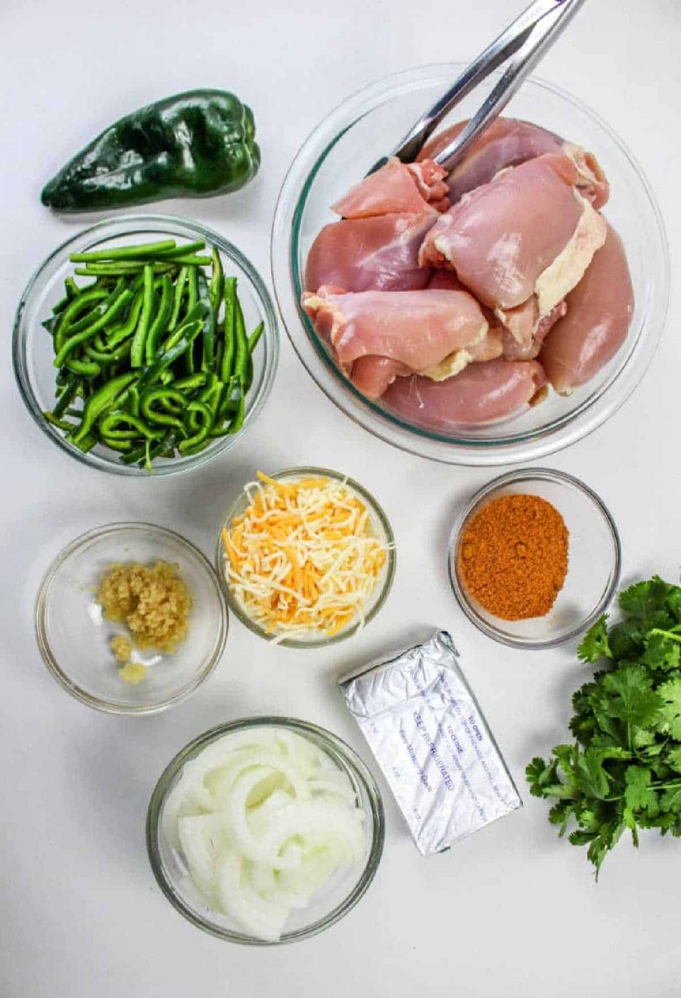 Ingredients for Chicken Poblano: raw chicken, poblano peppers, cheese, spices, onion, cream cheese, garlic, and cilantro—solid for a flavorful meal.