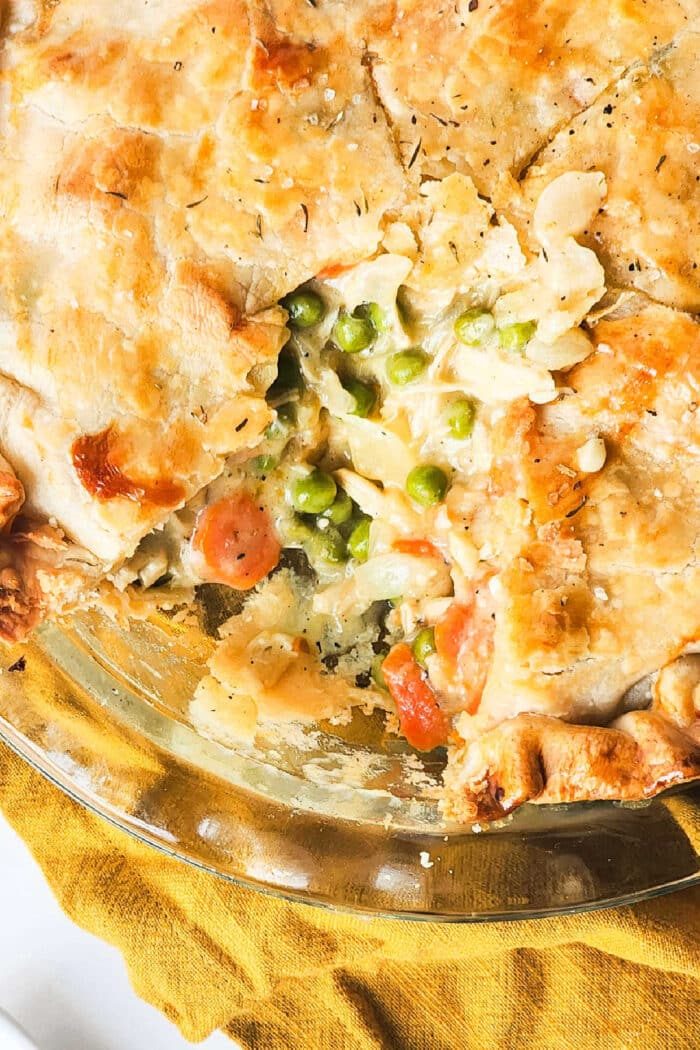 Close-up of a golden-brown chicken pot pie with a slice removed, revealing peas, carrots, and creamy filling inside—perfectly capturing the essence of a classic recipe made with cream of chicken soup.