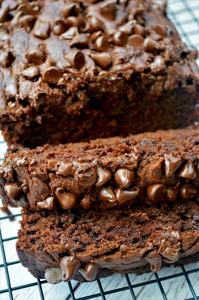 Sliced chocolate pumpkin bread topped with chocolate chips rests on a cooling rack, reminiscent of a rich chocolate pumpkin cake in its decadent allure.