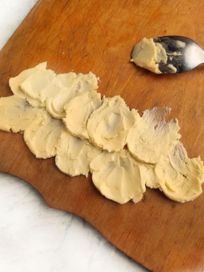 Mashed butter spread on a wooden cutting board alongside a festive spoon create the solid base for your Christmas butter board.