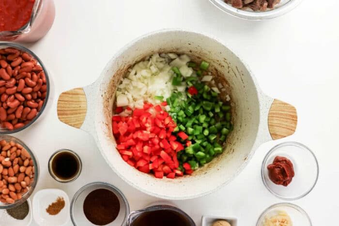 Diced onions, red bell peppers, and green bell peppers in a pot, surrounded by hearty chili ingredients—solid for a good chuck roast chili or classic beef chili.
