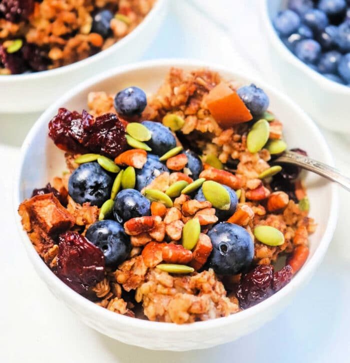 A bowl of oatmeal with blueberries, pumpkin seeds, and dried cranberries, reminiscent of slow cooker cinnamon oatmeal.