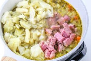 Simmering on the stovetop is a hearty Corned Beef and Cabbage Soup, filled with tender cabbage, savory cubed ham, and rich broth.