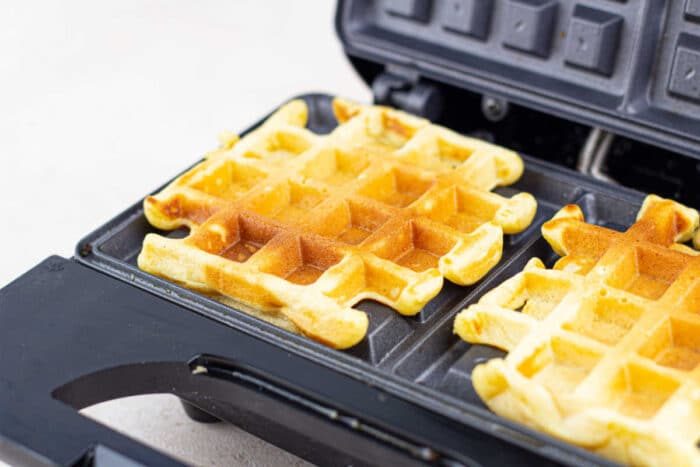 Golden corn waffles with a crispy exterior and tender, fluffy interior, served with toppings.
