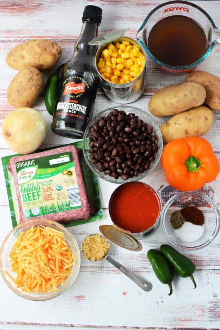 Ingredients for a Cowboy Casserole: potatoes, corn, black beans, cheese, beef, jalapeños, onion, spices, broth, and sauce—solid for an easy Crockpot Tex-Mex meal.
