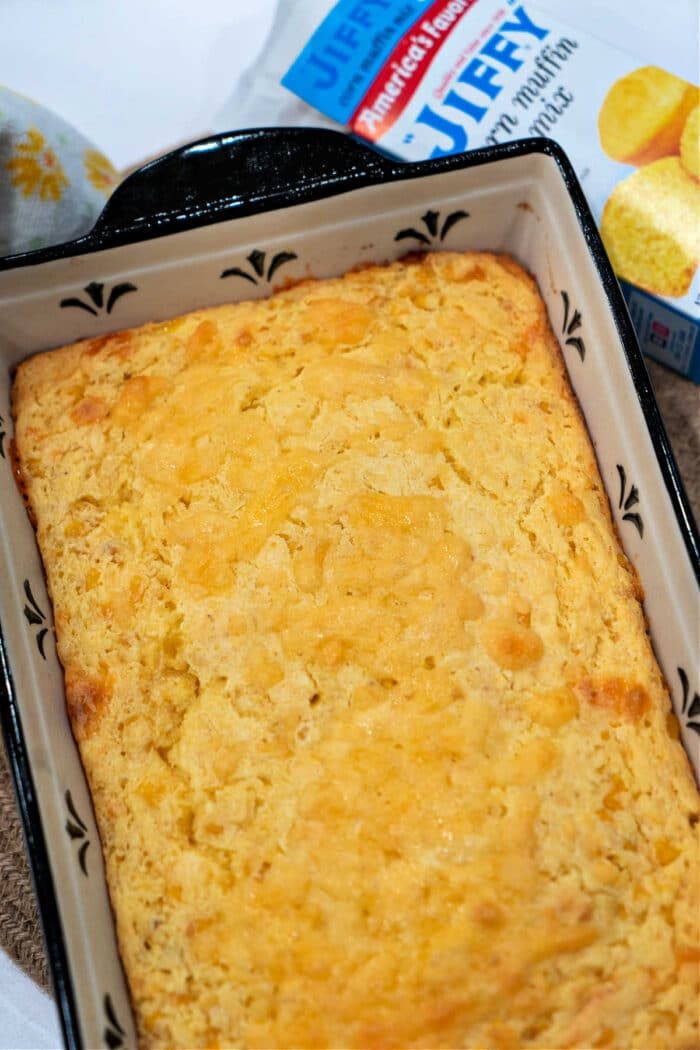 Baked cream corn pudding featuring a touch of cream cheese corn casserole goodness, with the Jiffy cornbread mix box in the background.