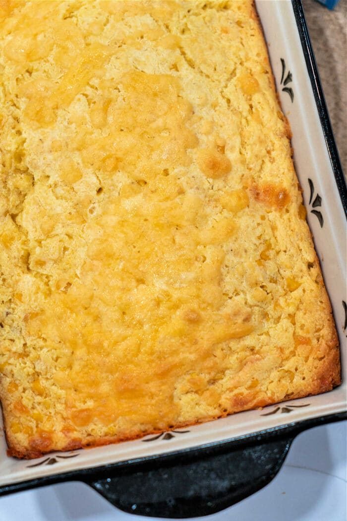 Golden cream corn casserole in a black and white baking dish, reminiscent of a delightful cream cheese corn casserole.