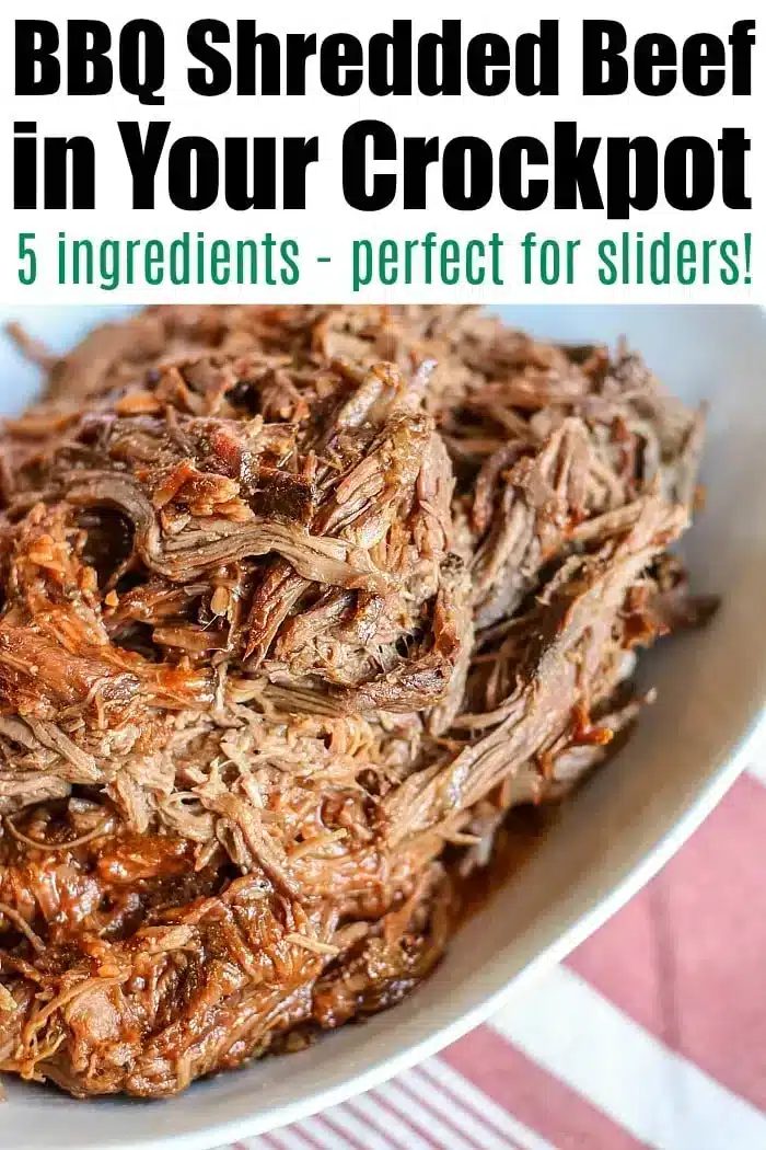 A close-up of a dish featuring crockpot BBQ shredded beef. The text at the top reads: "BBQ Shredded Beef in Your Crockpot" followed by "5 ingredients - solid for sliders!" The beef is served on a white plate with a red and white striped cloth underneath.