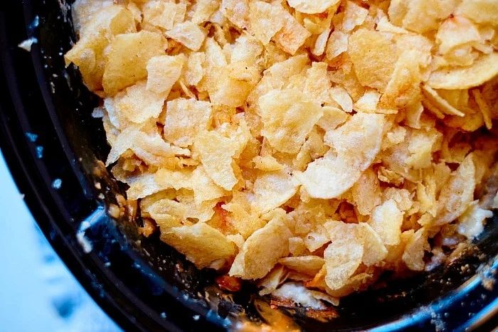 Close-up of crispy potato chips in a black bowl, reminiscent of the golden topping on crockpot funeral potatoes.
