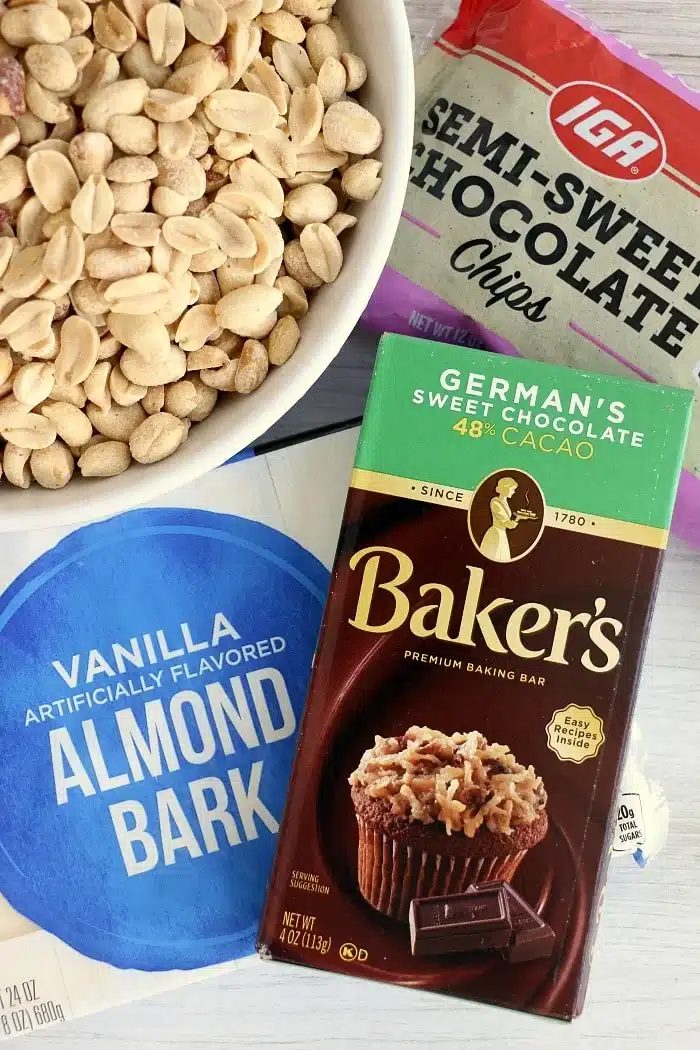 Bowl of peanuts, a bag of chocolate chips, almond bark, and a Baker's German's sweet chocolate bar—solid ingredients for making irresistible crockpot peanut clusters.