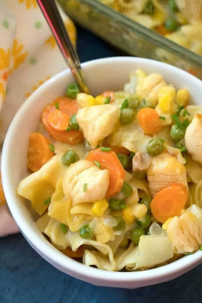 Bowl of creamy easy chicken pot pie casserole with carrots, peas, and corn, served with a fork in the bowl.