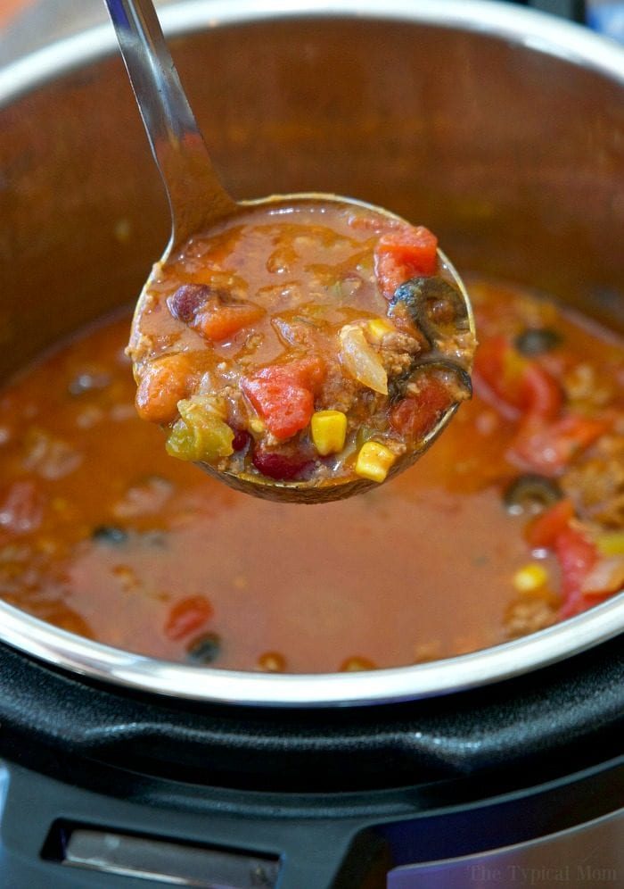 A ladle serving a hearty taco soup with beans, tomatoes, corn, and meat from the pot—a simple take on an easy Instant Pot taco soup recipe.