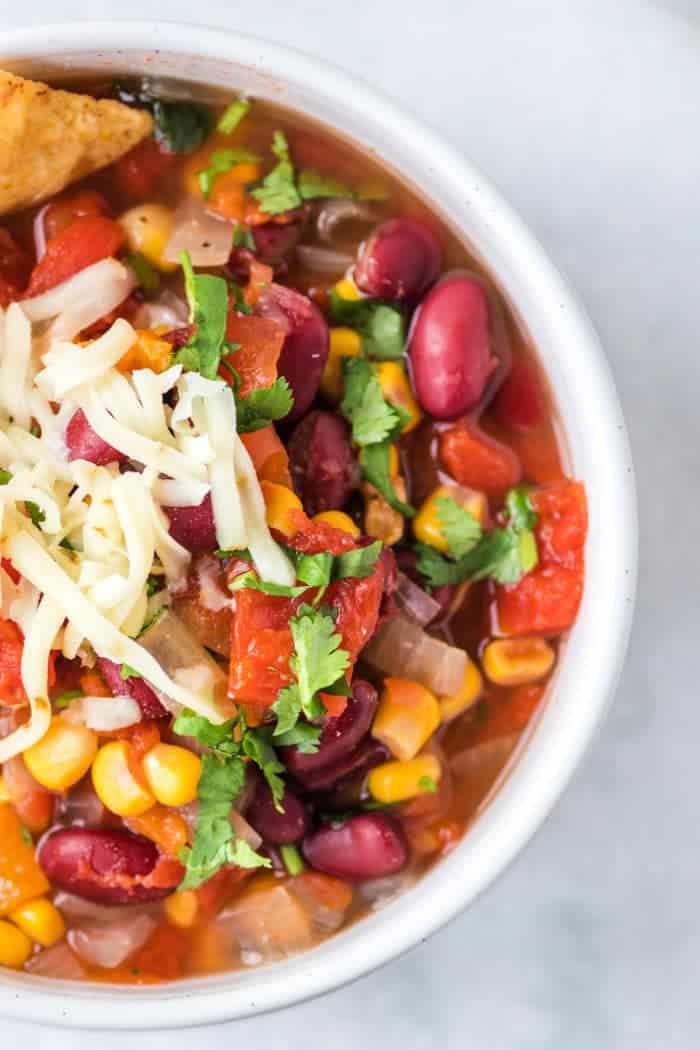 A bowl of taco soup with kidney beans, corn, tomatoes, and cilantro topped with shredded cheese captures the essence of an easy instant pot taco soup recipe.