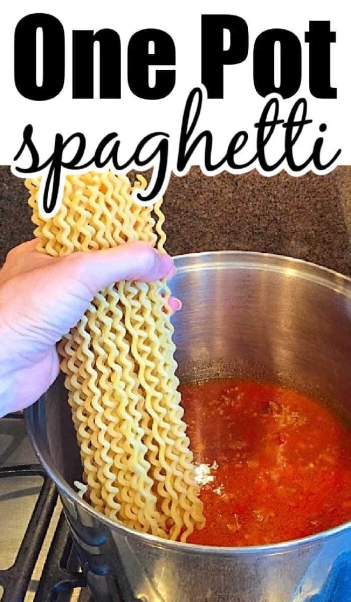 Hand holding wavy spaghetti noodles over a pot of red sauce on the stovetop; text reads One Pot Spaghetti, making dinnertime simple and good.