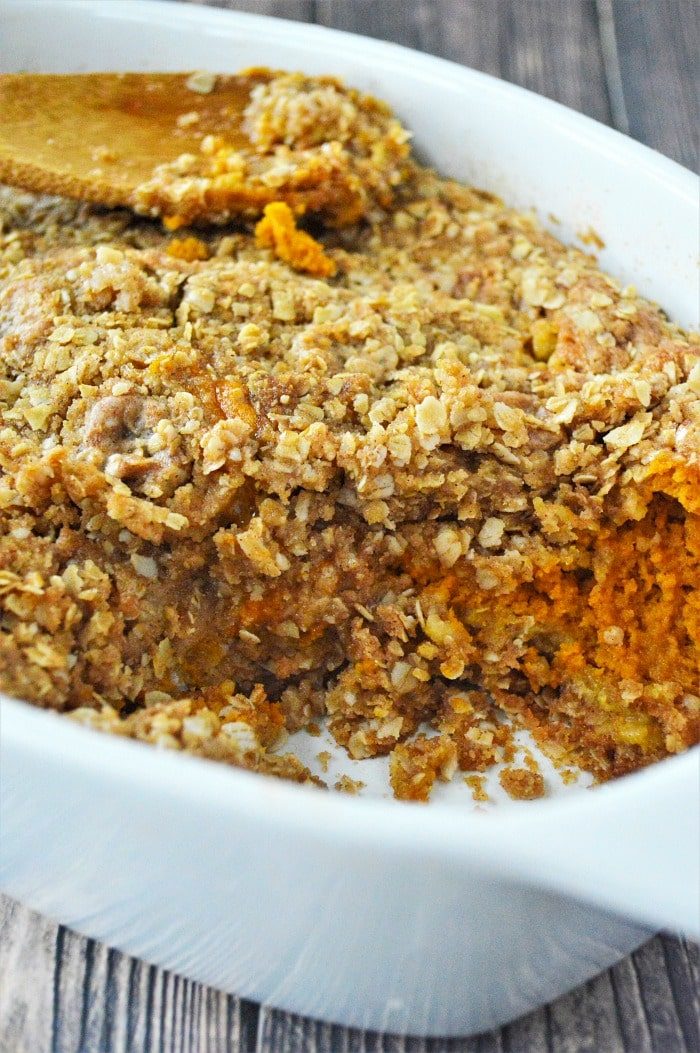 Baked sweet pumpkin crisp casserole with oat crumble topping in a white dish, reminiscent of a pumpkin crisp without cake mix.