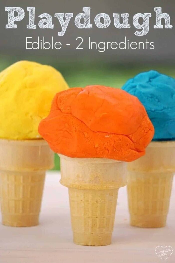 Three ice cream cones topped with colorful scoops of edible playdough in yellow, orange, and blue sit on a table.